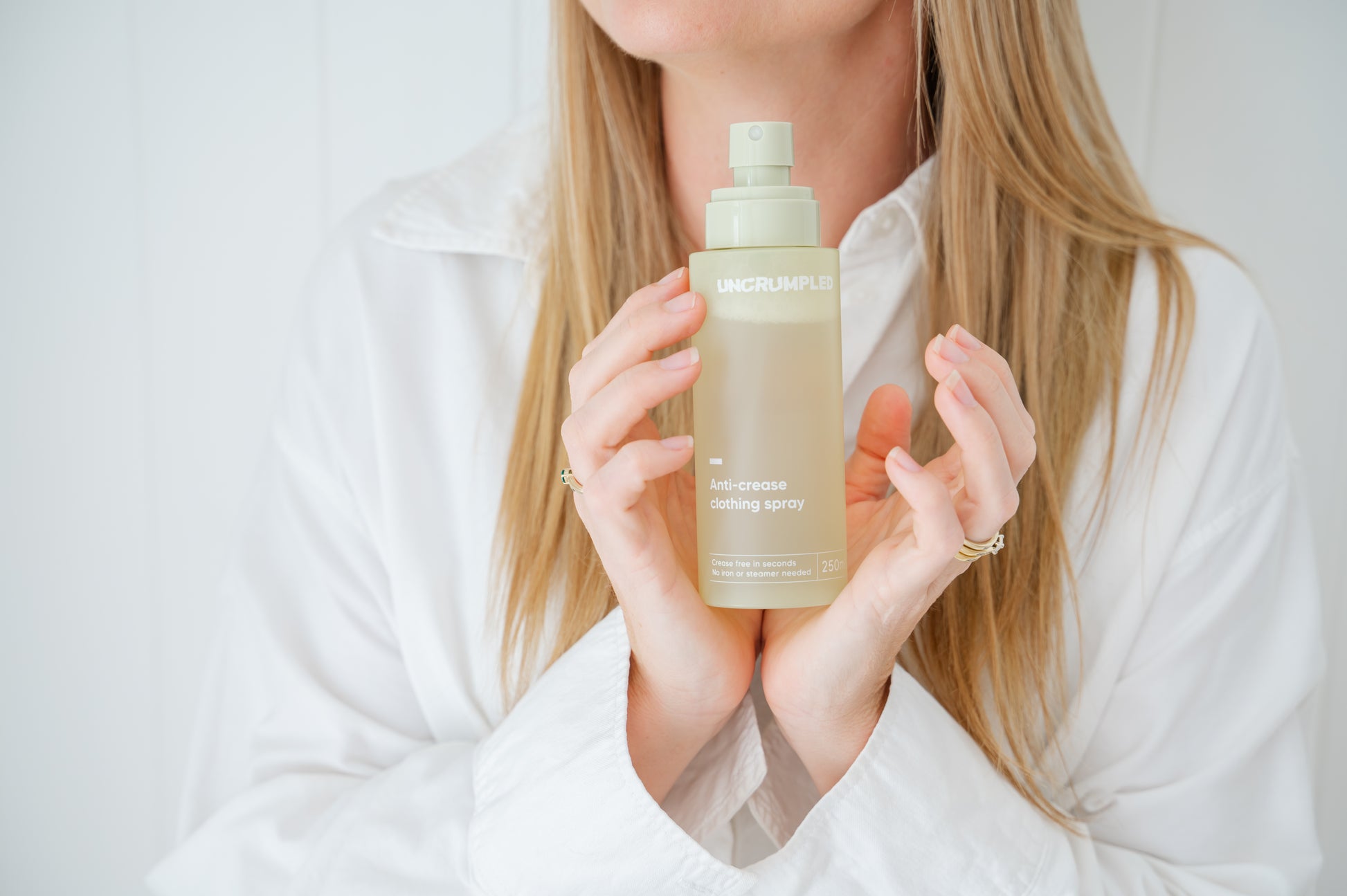 Person holding a regular-sized Uncrumpled anti-crease spray bottle with its cap off