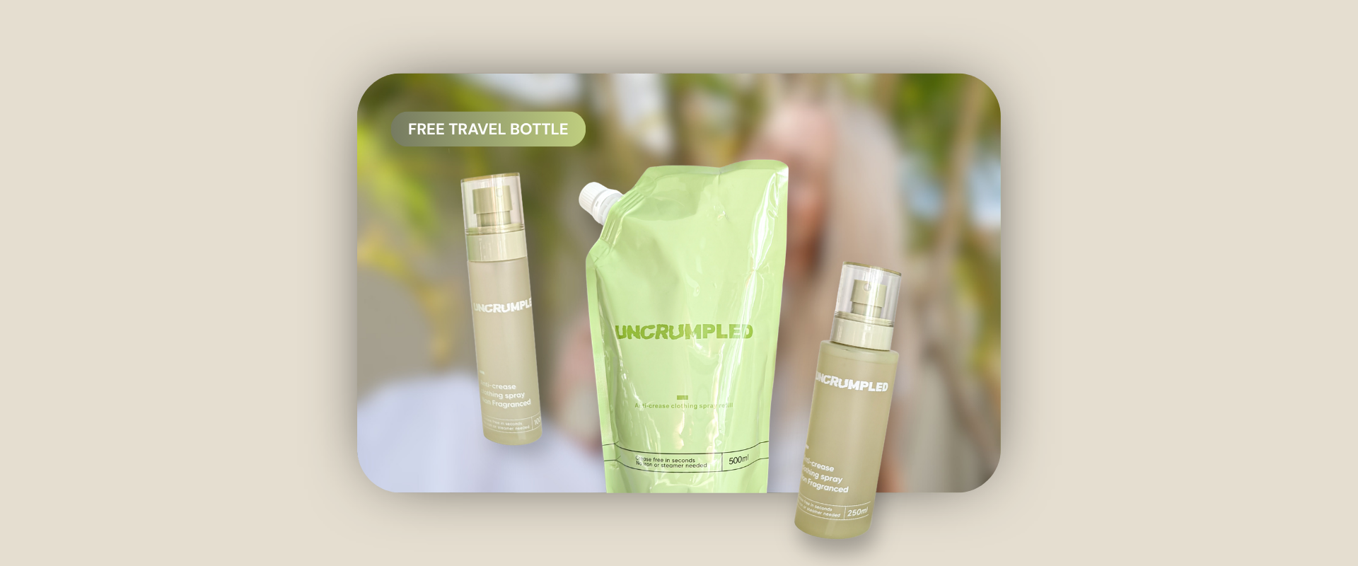 Three anti-crease products from Uncrumpled are displayed together on a rounded card over a beige background: a travel-sized bottle, a light green refill pouch, and a regular-sized bottle, with a blurred green-and-white background inside the card.